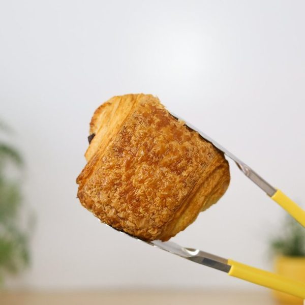 French Pain au Chocolat Bellbird Bakery held with yellow tongs