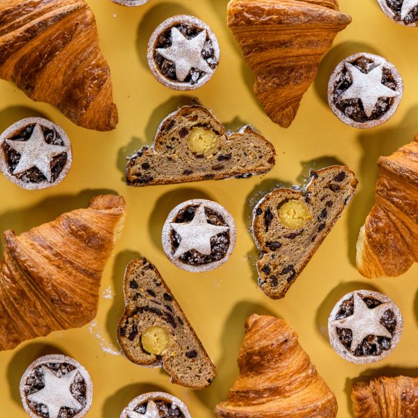 Christmas bakery products fruit mince tarts, croissants and Stollen on yellow background