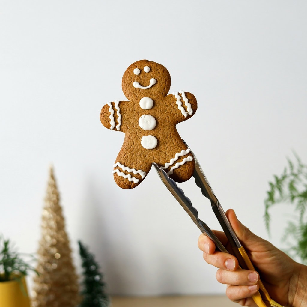 Gingerbread person with white icing held with tongs Bellbird Bakery