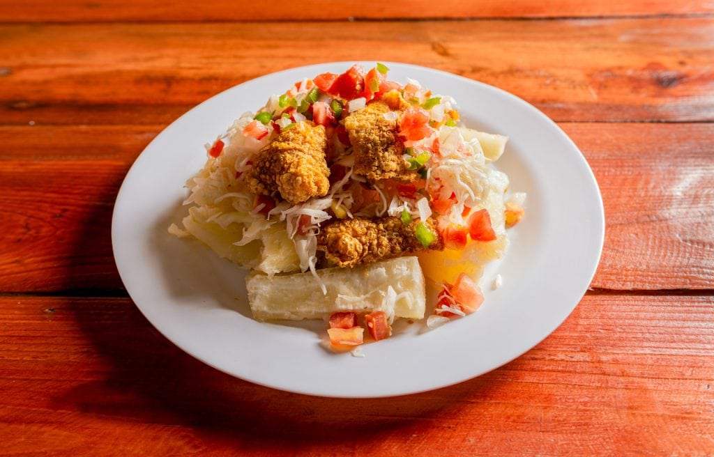 Latin food chicharron con yuca served on wooden table. Nicaraguan dish chicharron with cassava on the table.