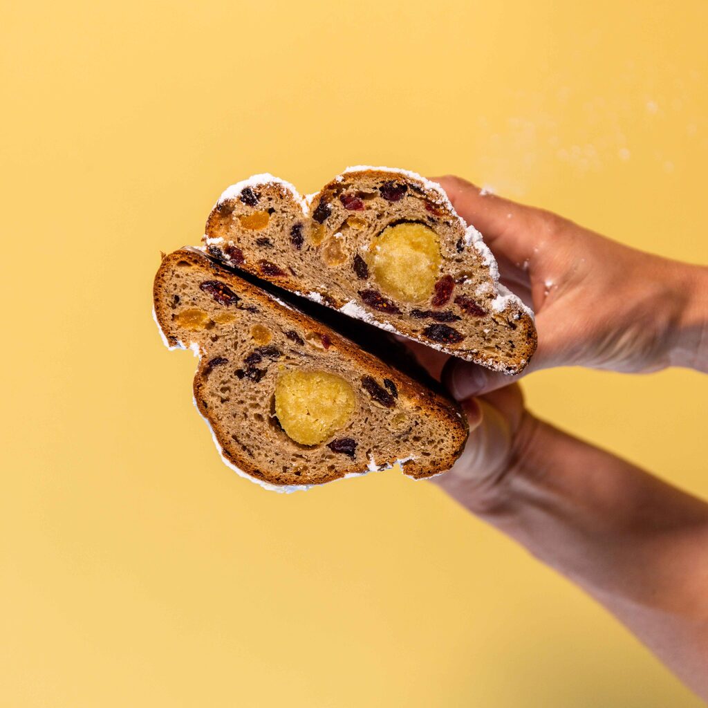 Stollen German fruit bread cut open with marzipan on yellow background