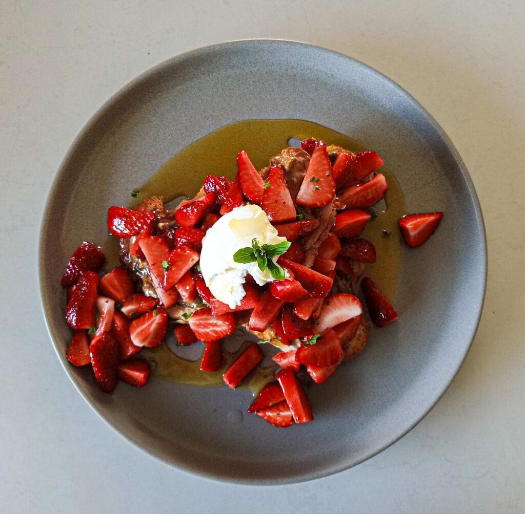 Leftover vegan croissant and mint strawberry salad with a dollop of coconut yoghurt on a grey plate, seen from above Bellbird Bakery