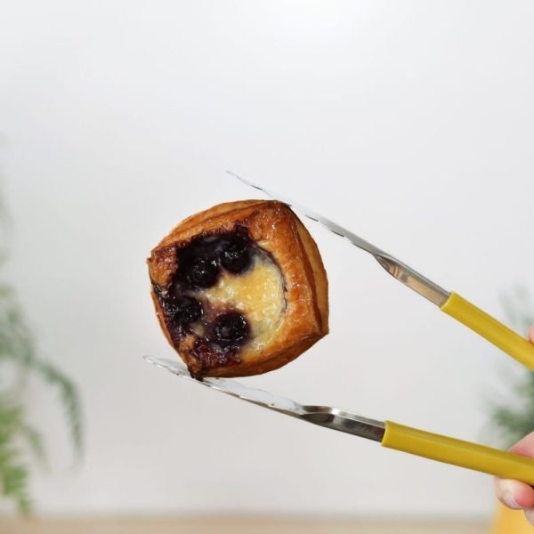 Mini Blueberry Danish held by yellow tongs at Bellbird Bakery