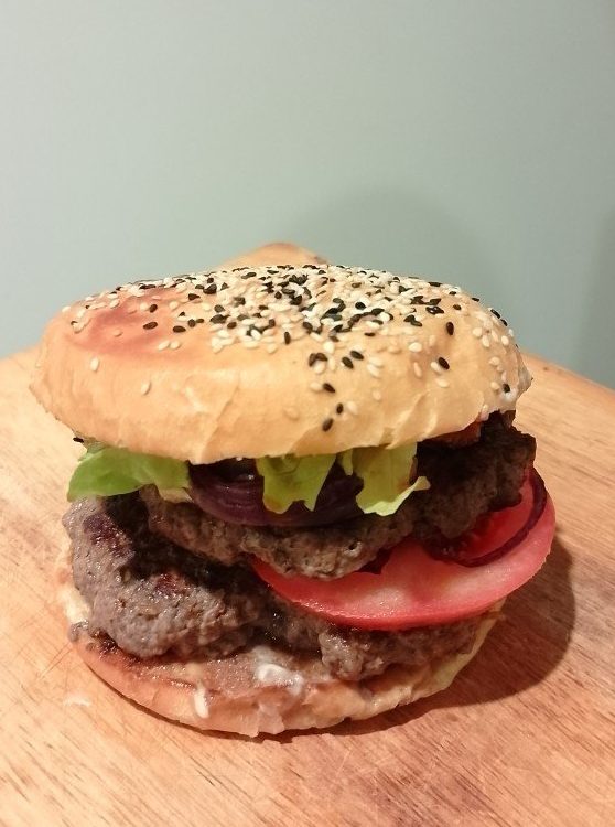 Double beef burger on brioche bun with sesame seeds, with tomato, red onion and lettuce