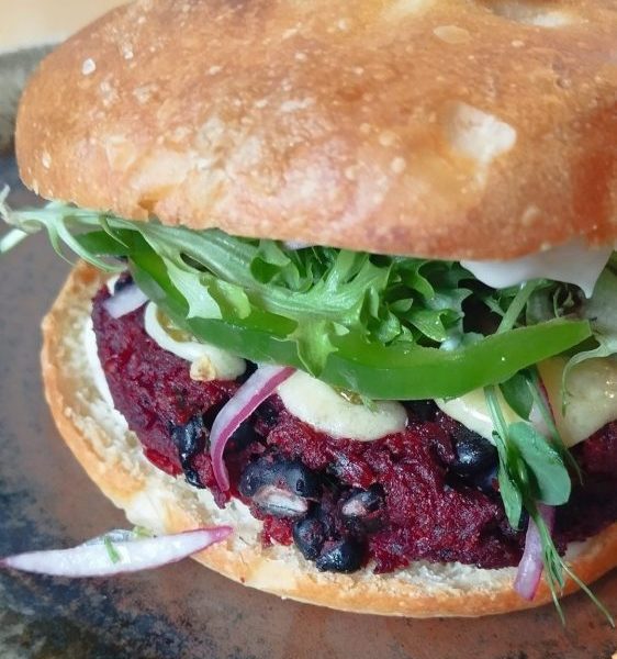 Beetroot Black Beans Burger with red onion, capsicum and cheese on a focaccia roll from Bellbird Bakery