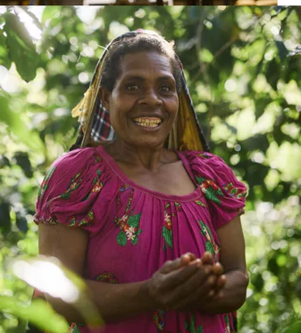Lady in pink top holding coffee berries in PNG