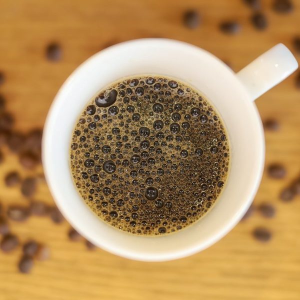 Prima black Filter Coffee in a cup with scattered beans seen from above