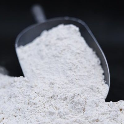 Aluminium scoop with bread flour on black background