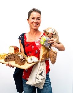 Alice holding a lot of different Bellbird Bakery breads to show the variety of way bread can be stored
