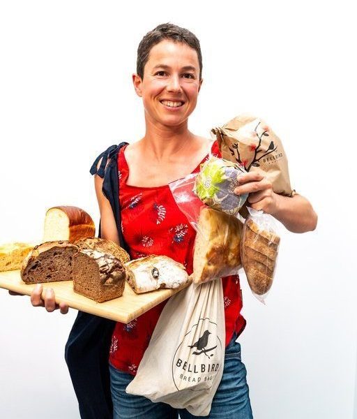 Alice holding a lot of different Bellbird Bakery breads to show the variety of way bread can be stored