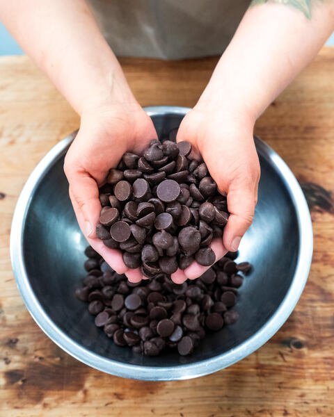Hands holding Weave Chocolate Drops over a bowl at Bellbird Bakery