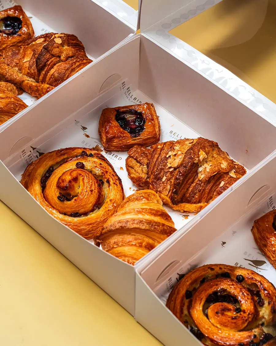 The Classic Box on yellow Background with Croissant, Pain Aux Raisins, Almond Croissiant and Mini Fruit Danish