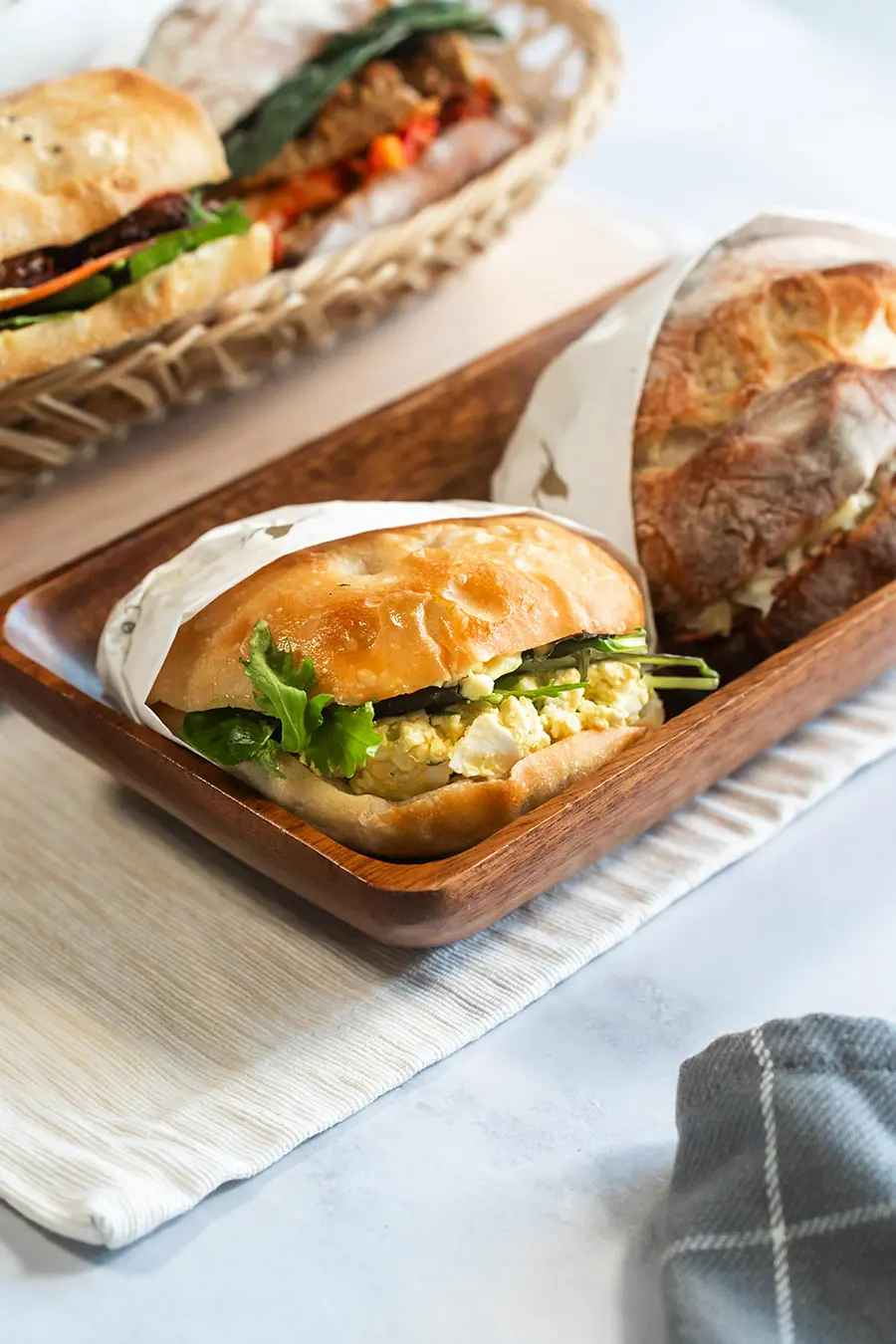 Egg Sandwich in wood basket next to other sandwiches from Bellbird Bakery