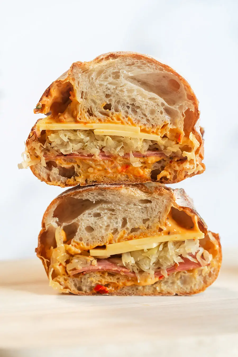The Reuben Sandwich cut in half on Wood Board on white background