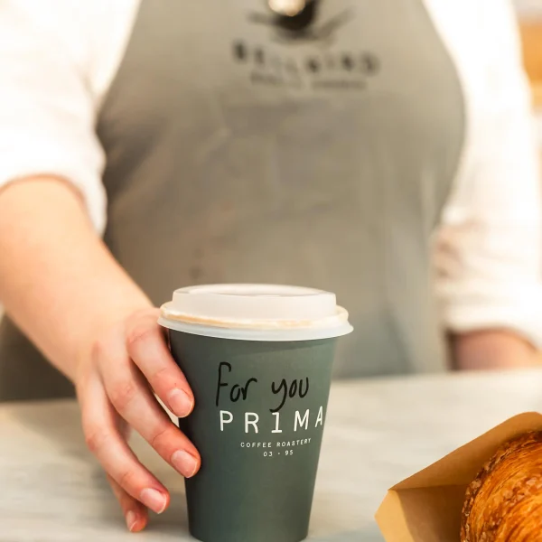 Coffee Cup handed over counter with Pastry in bag