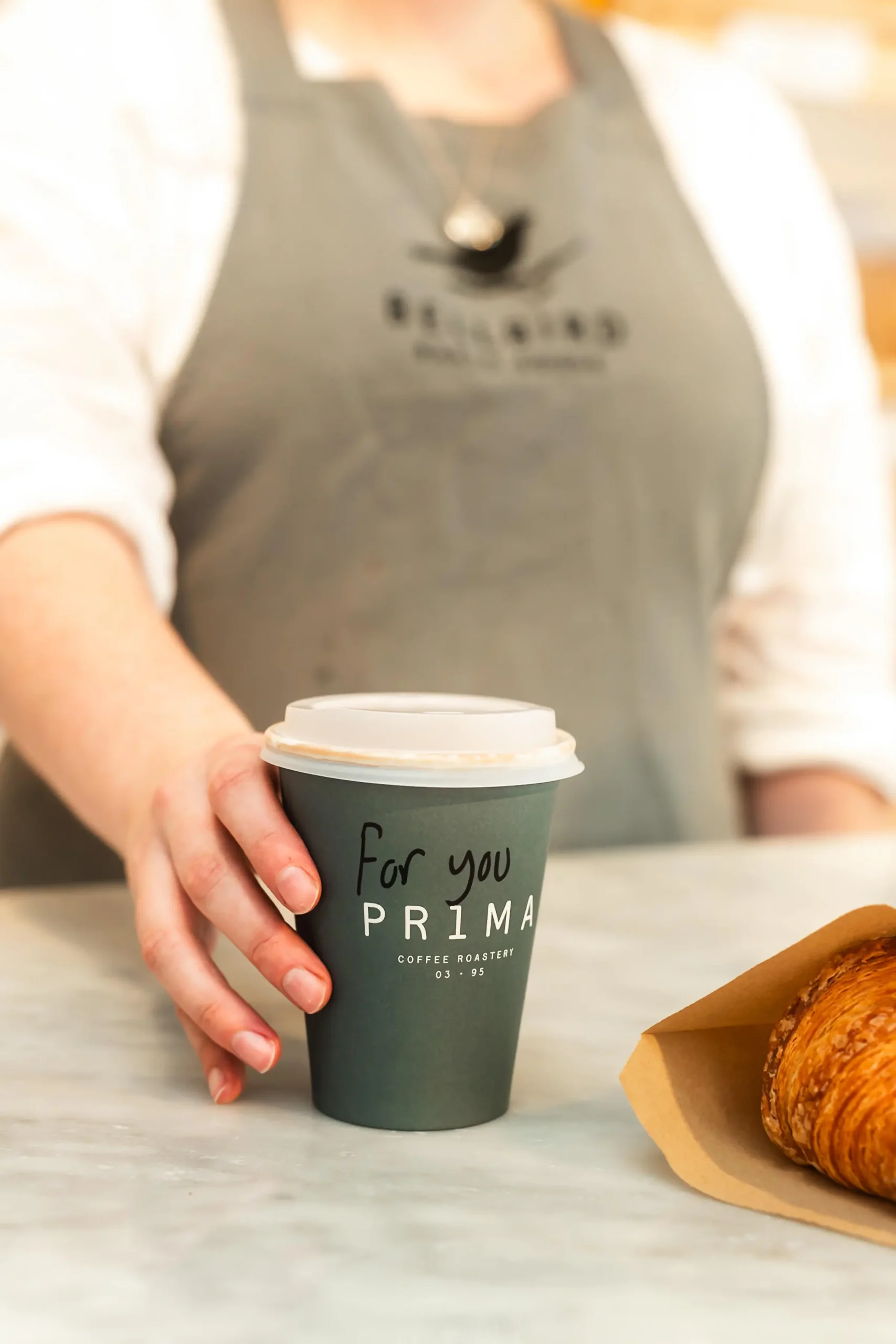 Coffee Cup handed over counter with Pastry in bag