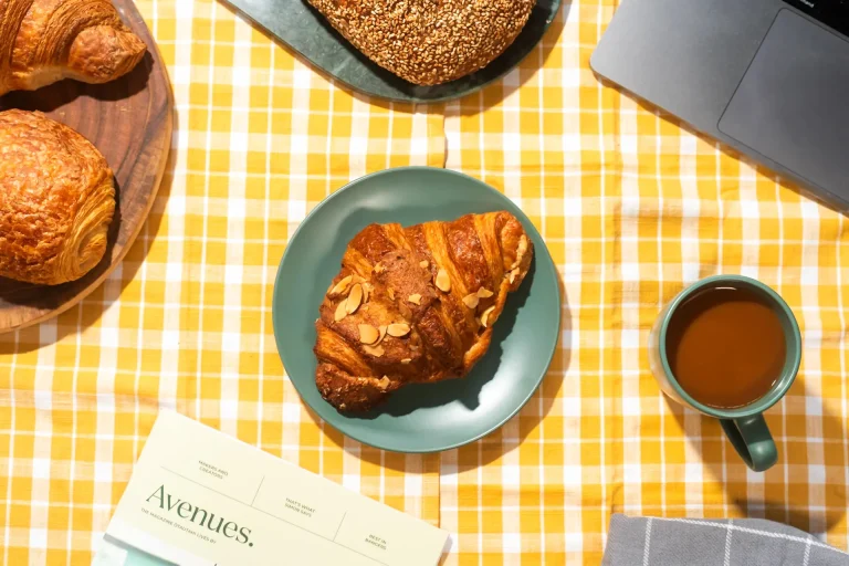 An Almond Croissant with coffee on a yellow tablecloth