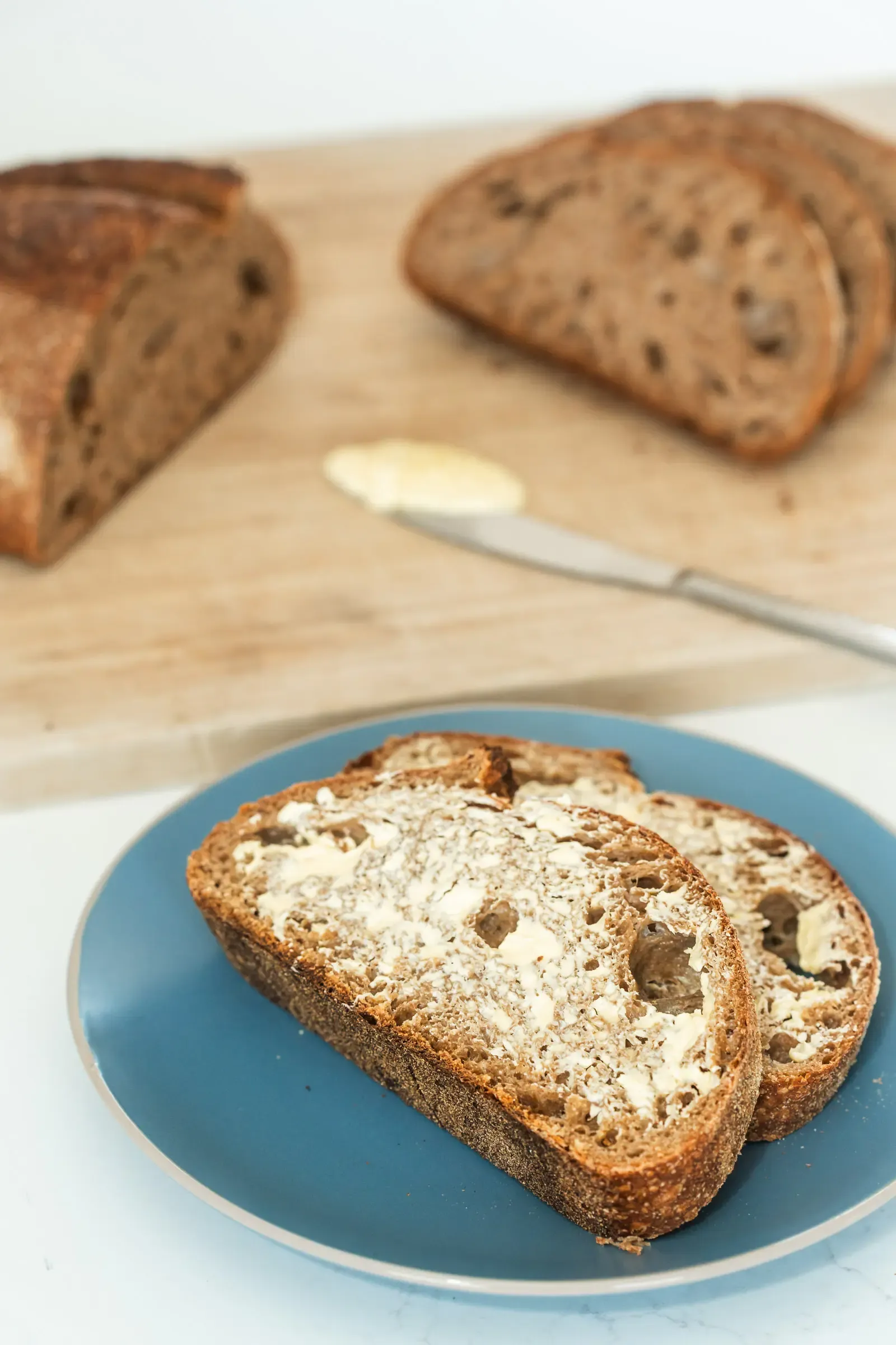 Organic Wholewheat Sourdough sliced and buttered on bread board