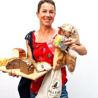 Alice holding a lot of different Bellbird Bakery breads to show the variety of way bread can be stored