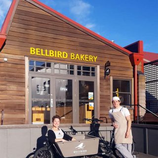 Alice and Jeremy with the cargo bike outside of Bellbird Bakery at The Tannery