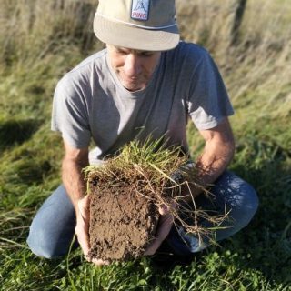 Dave holding a block of soil on a sunny regenerative farm