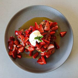 Leftover vegan croissant and mint strawberry salad with a dollop of coconut yoghurt on a grey plate, seen from above Bellbird Bakery